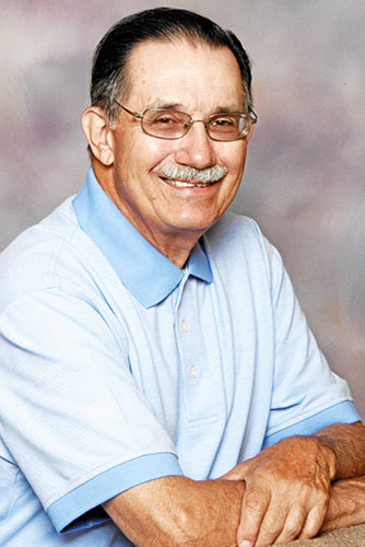 A man with glasses and a mustache wearing a blue shirt.